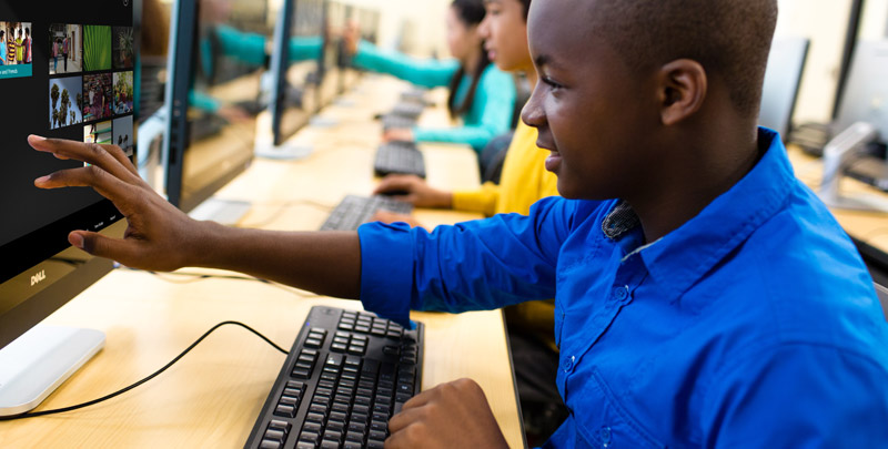 Black boy, and racially-diverse group of children using a computer