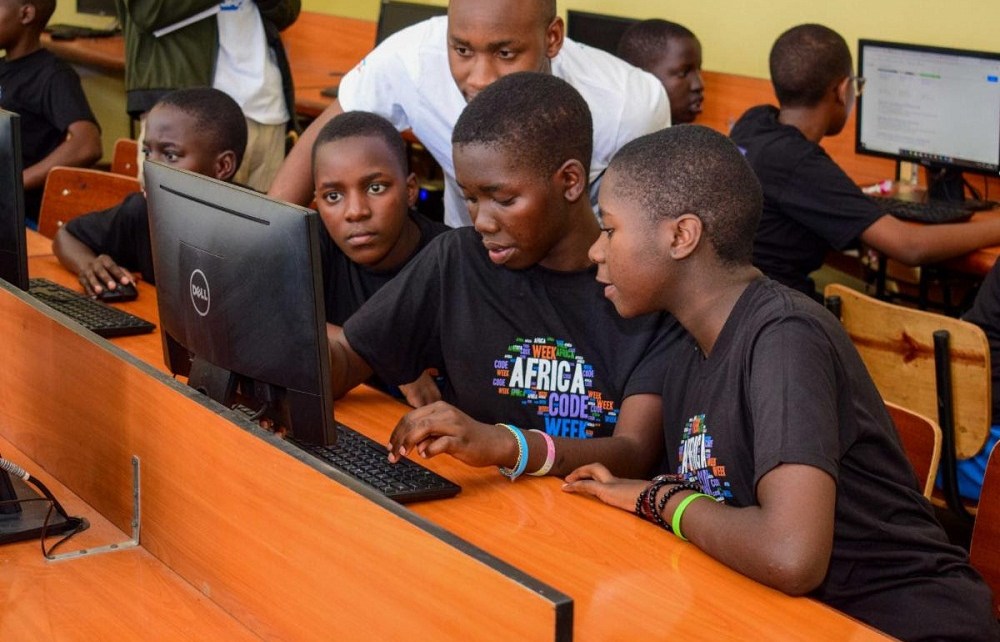 Group of Black boys in a computer lab being guided by their instructor. The instructor is a Black man.