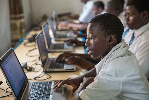 Group of Black boys in uniforms, using laptops in a classroom Group of Black boys in uniforms, using laptops in a classroom